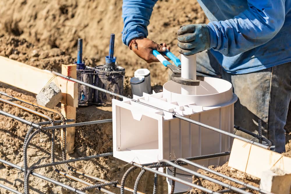 plumber installing pvc pipe at construction site